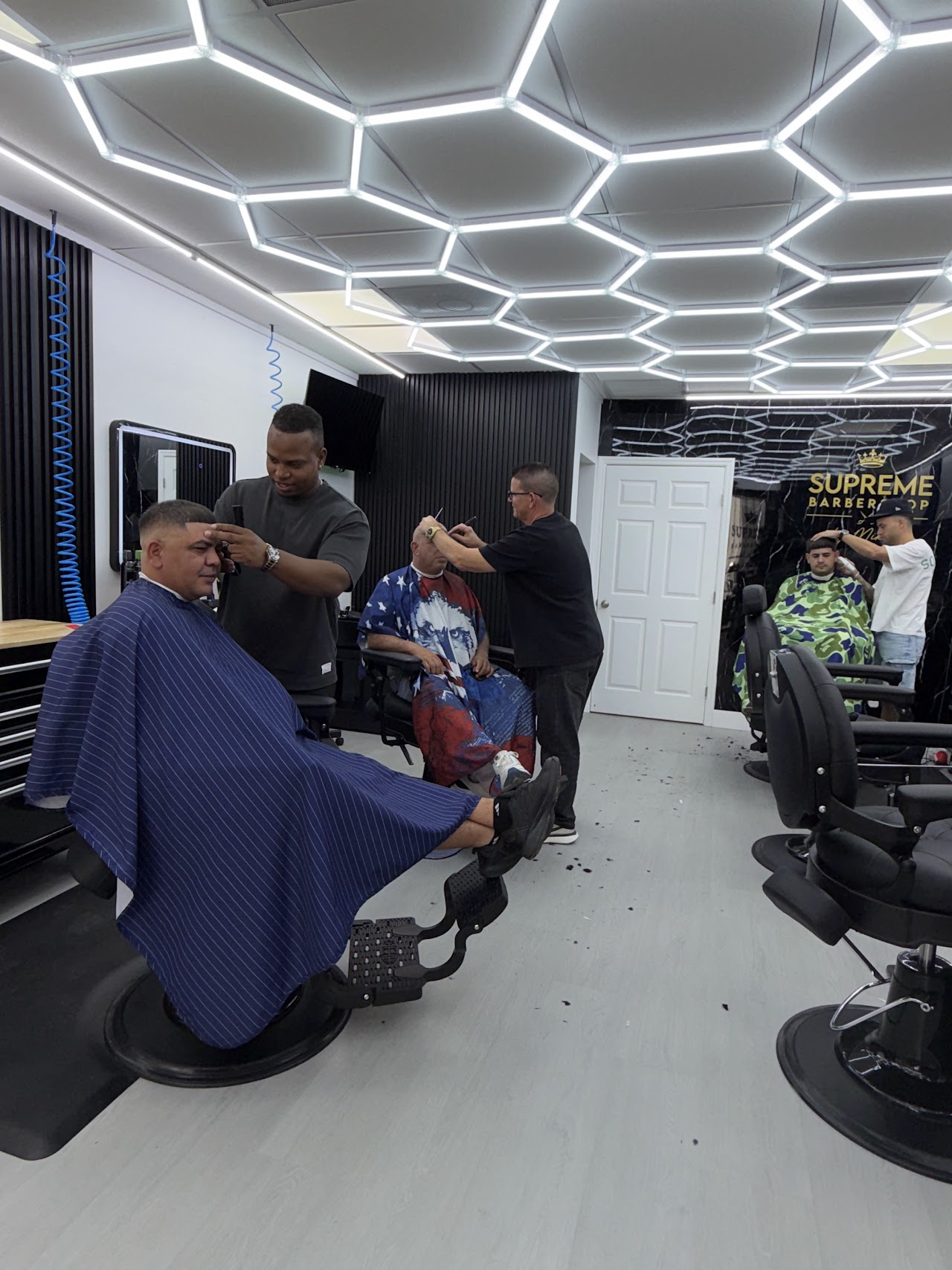 Barbers at Supreme Barbershop by Mikki giving haircuts to clients