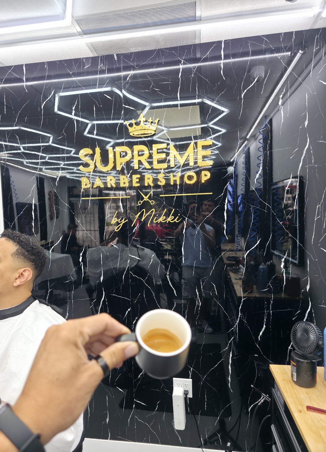 Close up of the gold Supreme Barbershop by Mikki crown emblem on black marble